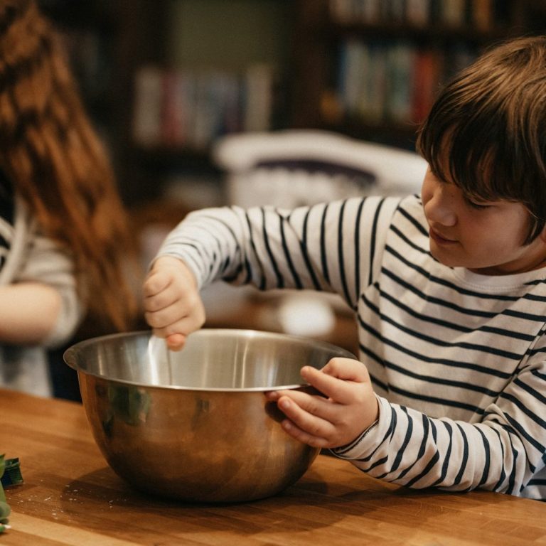 Gemeinsam kochen und genießen Kind bereitet gemeinsam mit einer erwachsenen Person eine Mahlzeit in der Küche zu