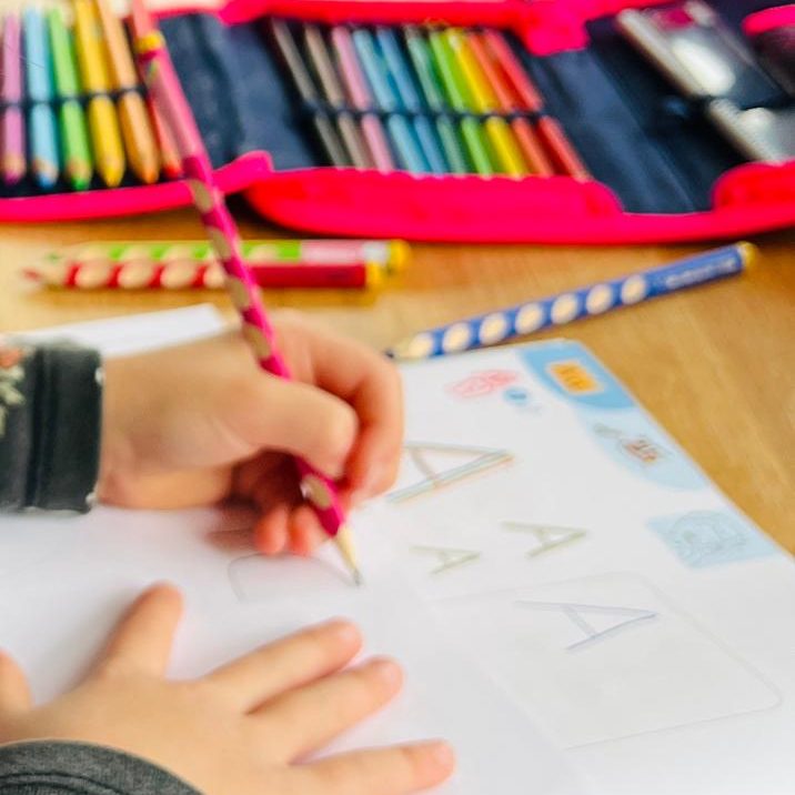 Kinderhände bearbeiten ein Arbeitsblatt am Tisch.